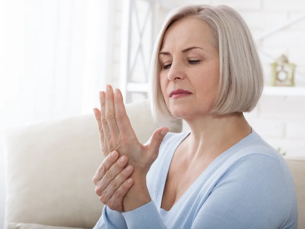 Frau massiert ihre arthritische Hand und Handgelenk